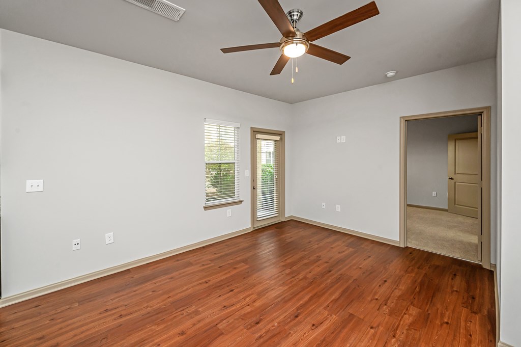 A room with a ceiling fan and wooden flooring.